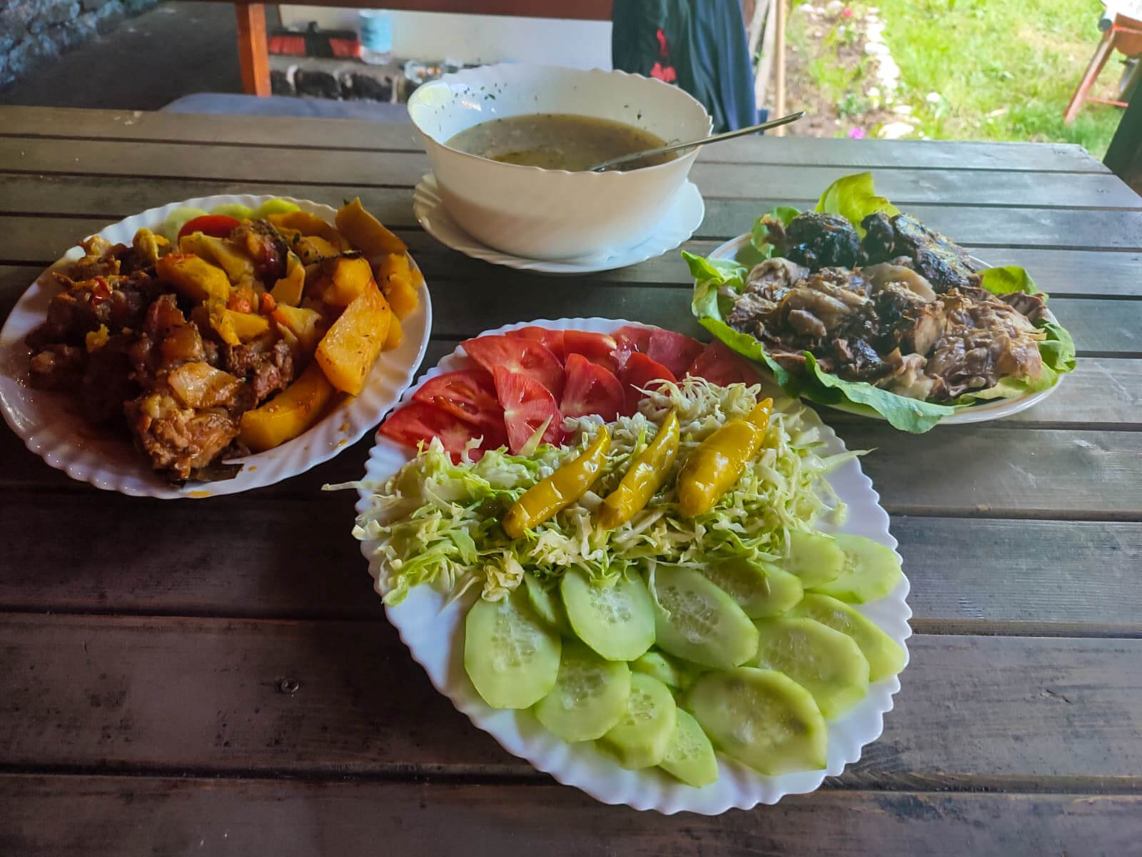 čorbica, salata, krompir i meso ispod sača izlozeni na tanjirima