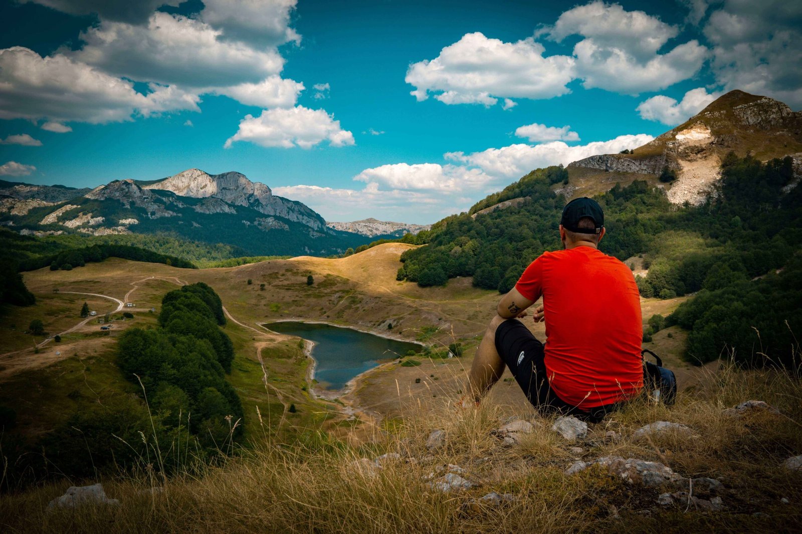 momak sjedi na kamenu i posmatra orlovacko jezero ispred njega