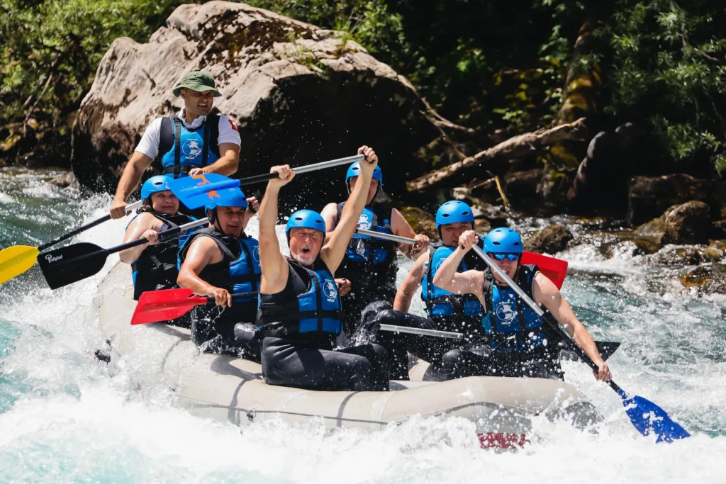 Naslovna A diverse group of people rafting down a river, capturing the thrill of outdoor adventure in a natural setting.