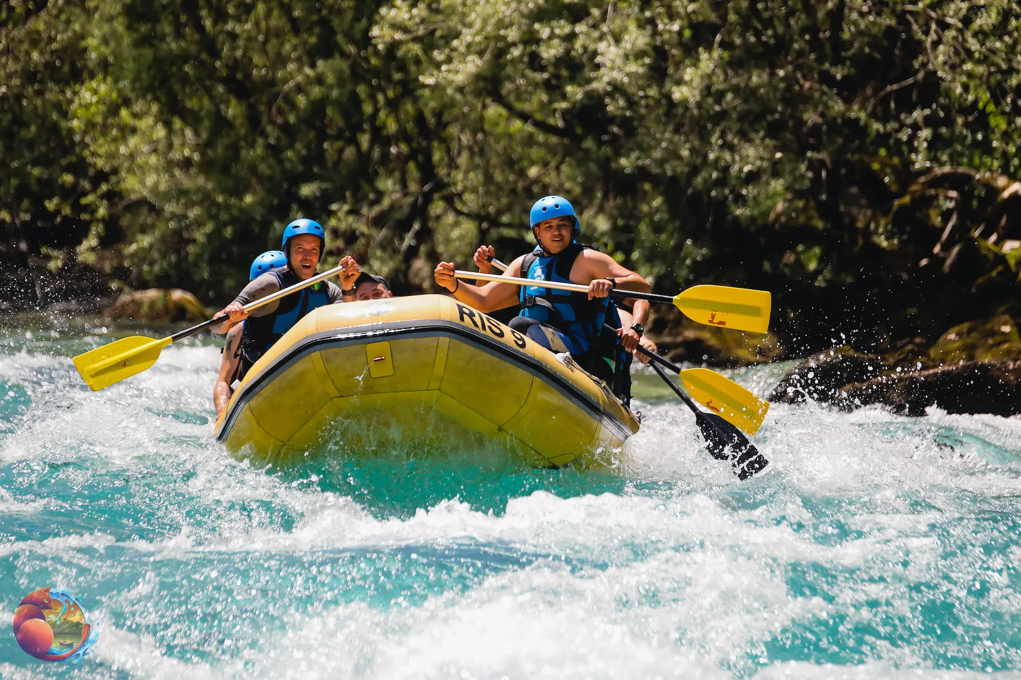 Naslovna A group of people paddling together in a raft on a flowing river, surrounded by lush greenery.
